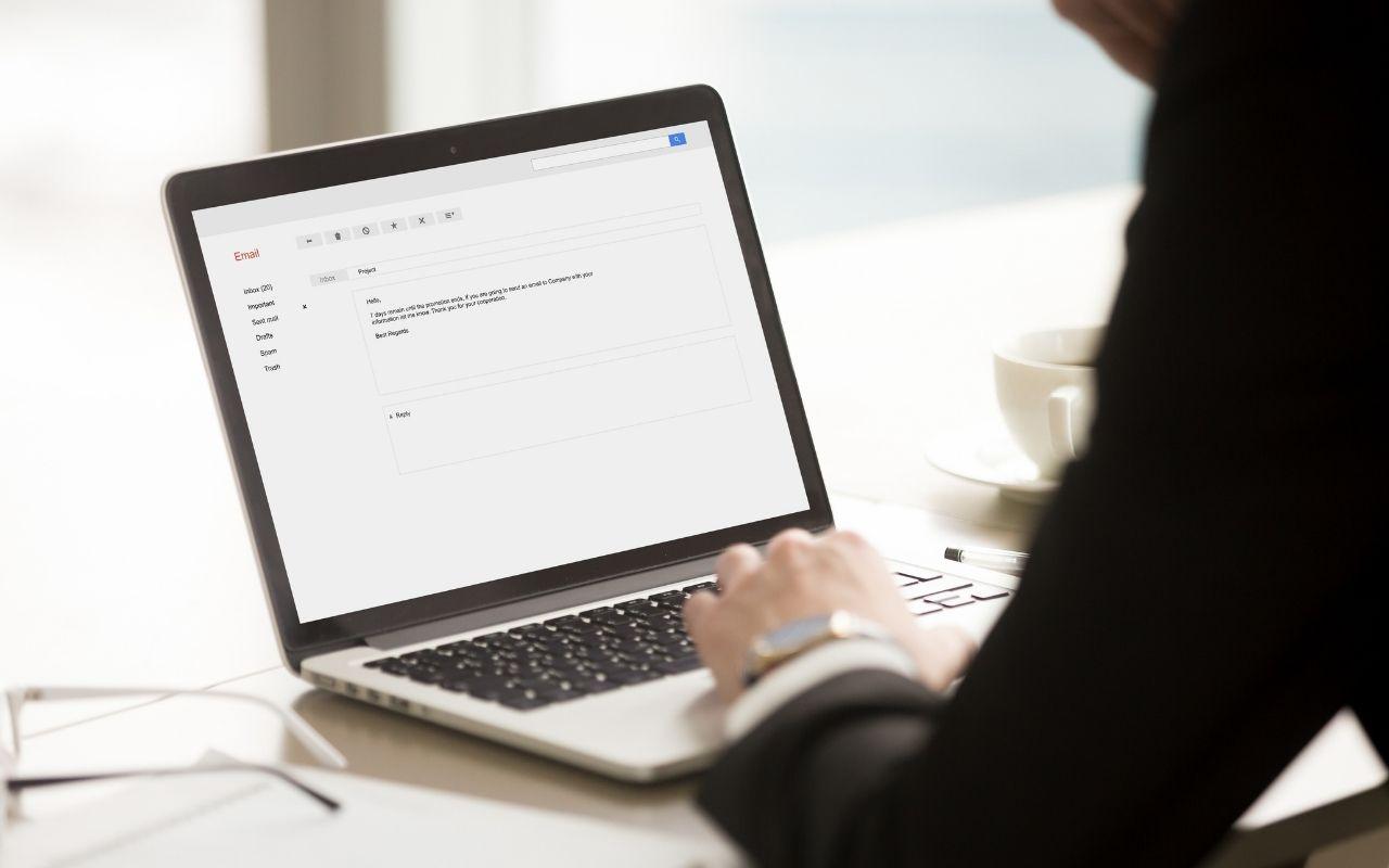 Person typing on a laptop with an email draft open on the screen, representing following up on a job application.
