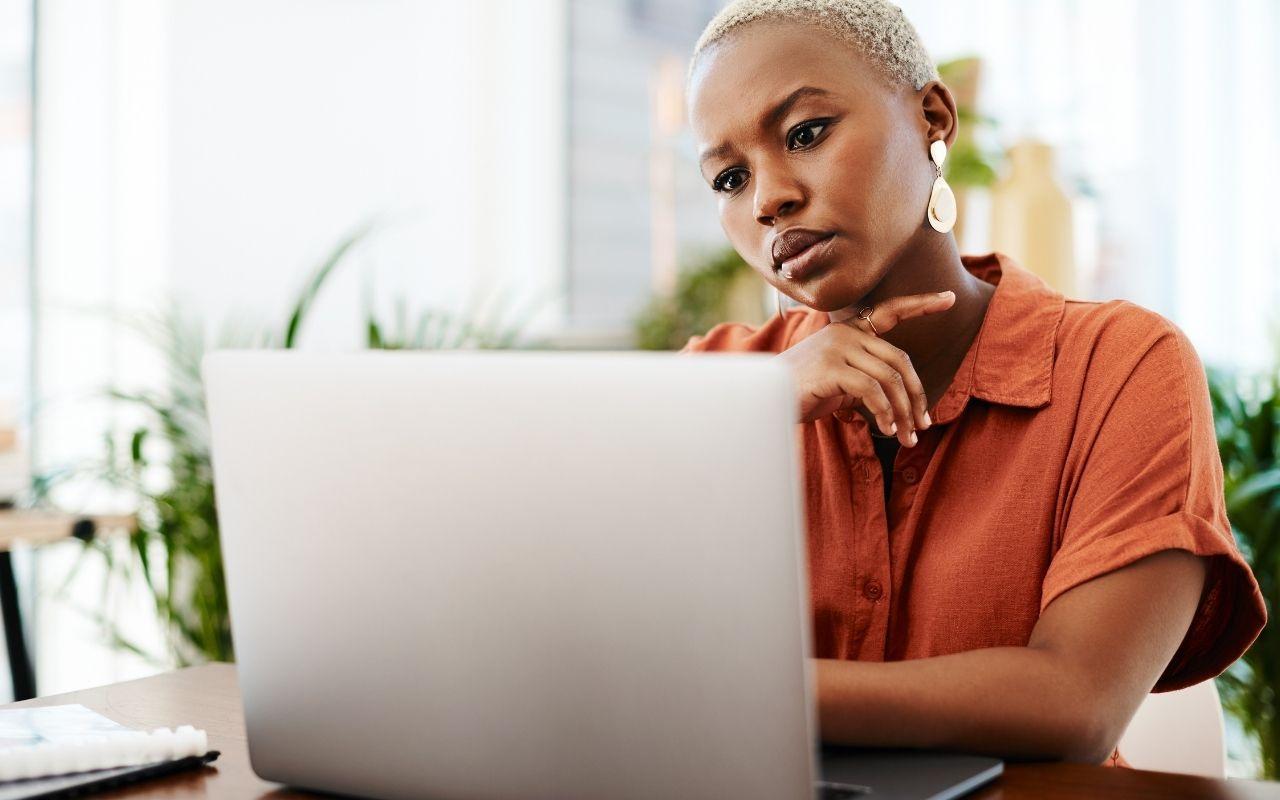 A professional thoughtfully focusing on a laptop while writing a career change cover letter.