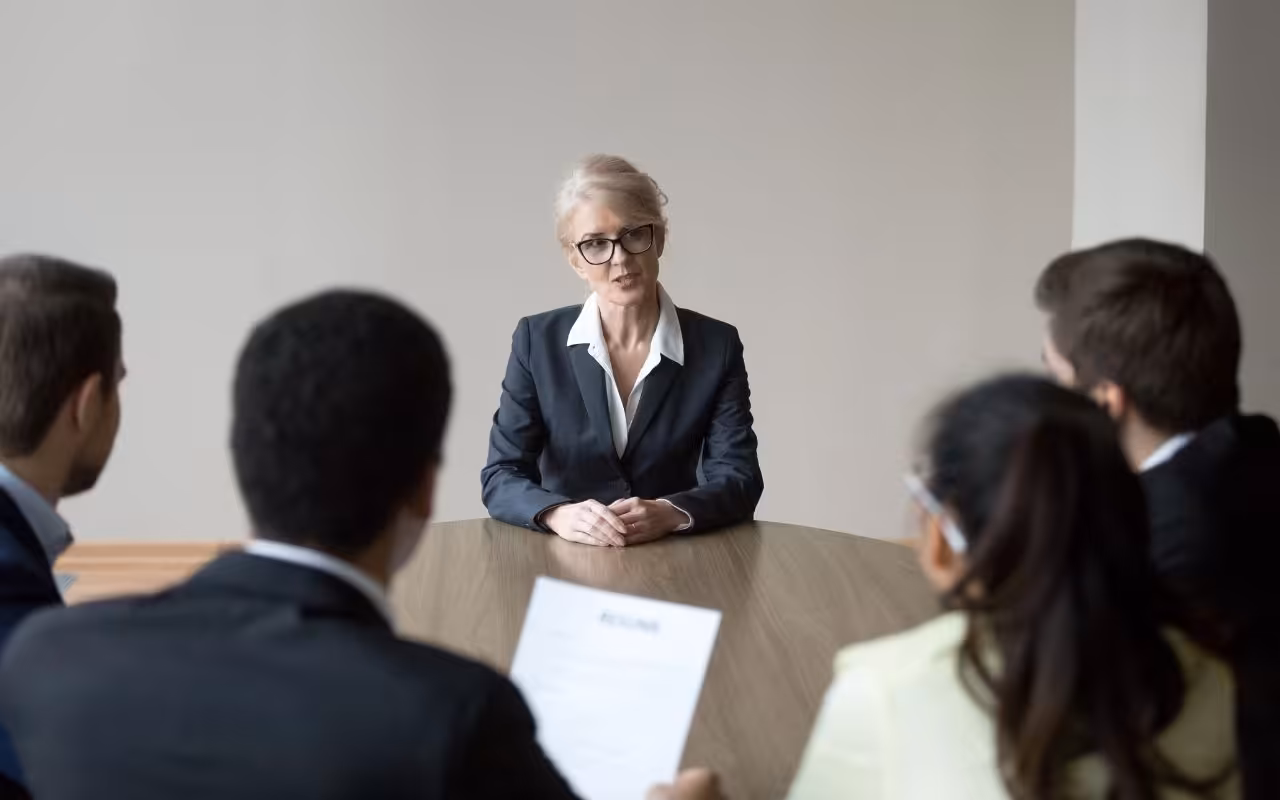 A professional woman over 50 confidently interviews with a panel, symbolizing a successful career change later in life.