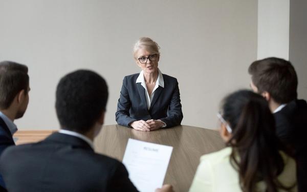 A professional woman over 50 confidently interviews with a panel, symbolizing a successful career change later in life.