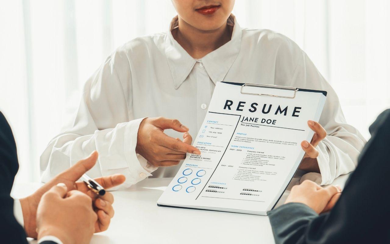 A job candidate points to the education and certifications section of their resume during an interview.
