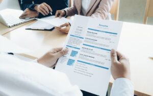 A person holds a professional resume highlighting job titles like Senior Designer, representing the use of accurate, ATS-friendly job titles that support job search success.