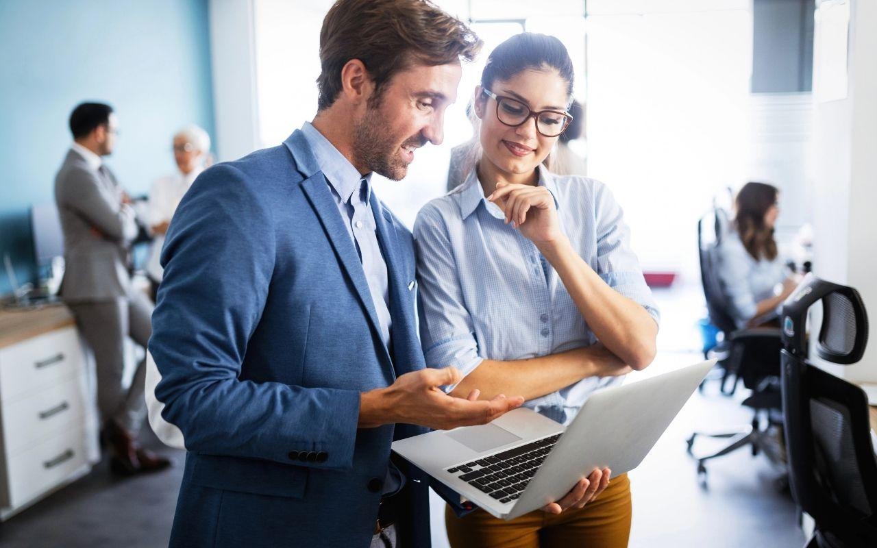 An employee discussing project details on a laptop with a manager in a modern office.